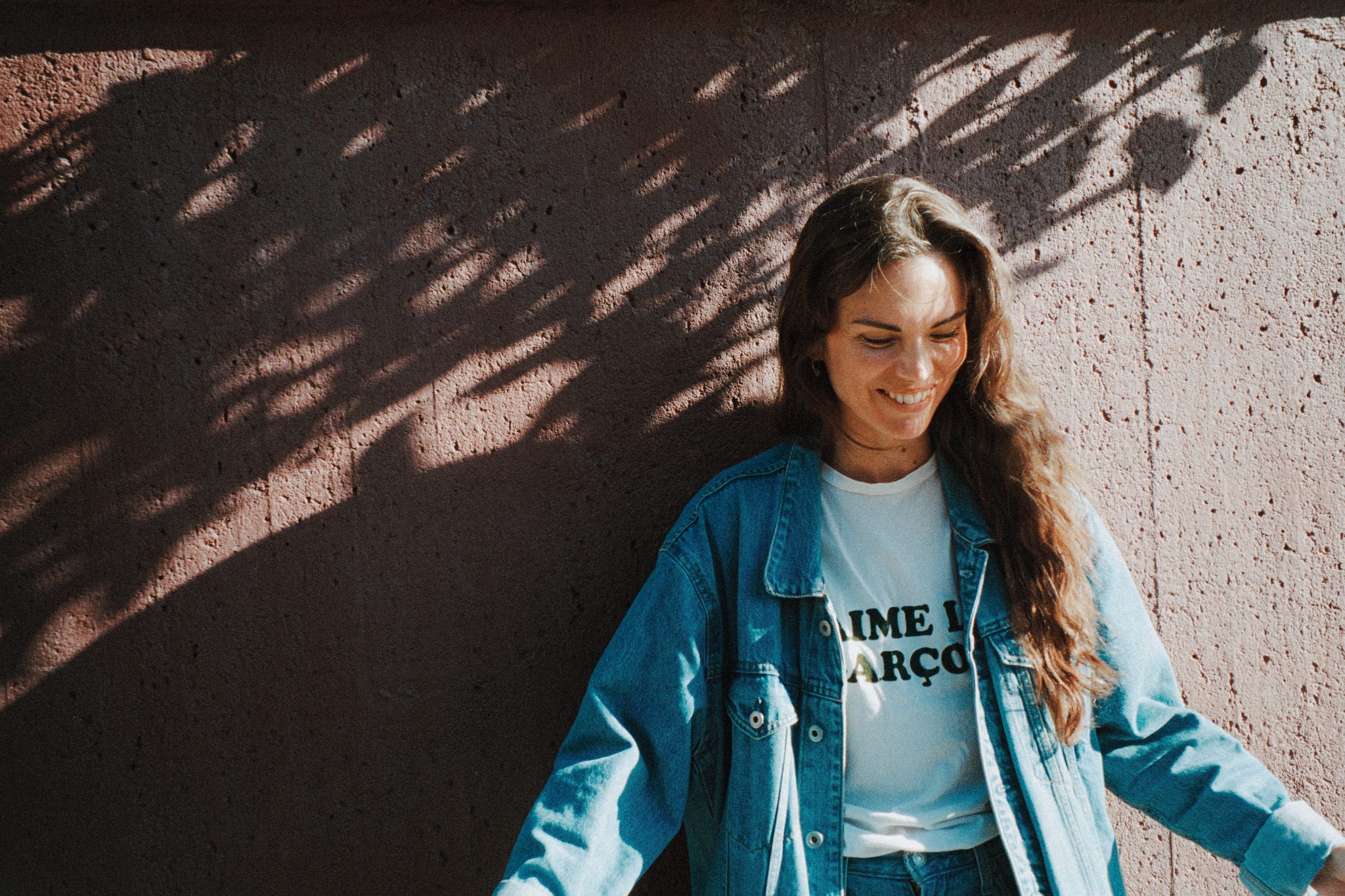 Kvinna står framför vägg utomhus i solsken.