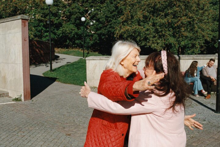 Två kvinnor omfamnar varandra på ett torg.