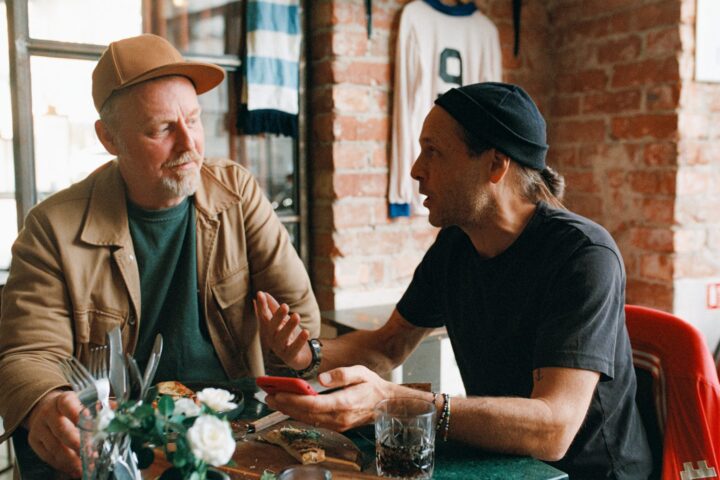 Två män sitter och samtalar i krogmiljö.