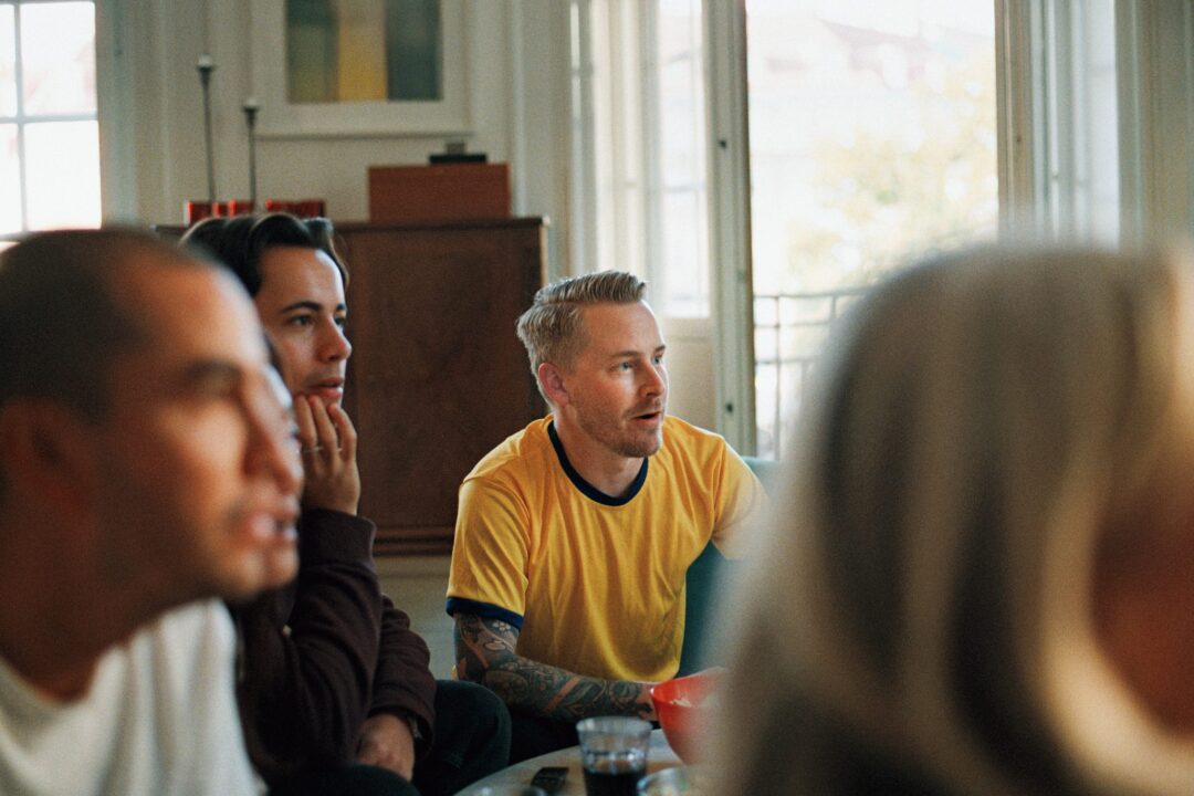 Tre män med fokuserad sitter framför tv:n.