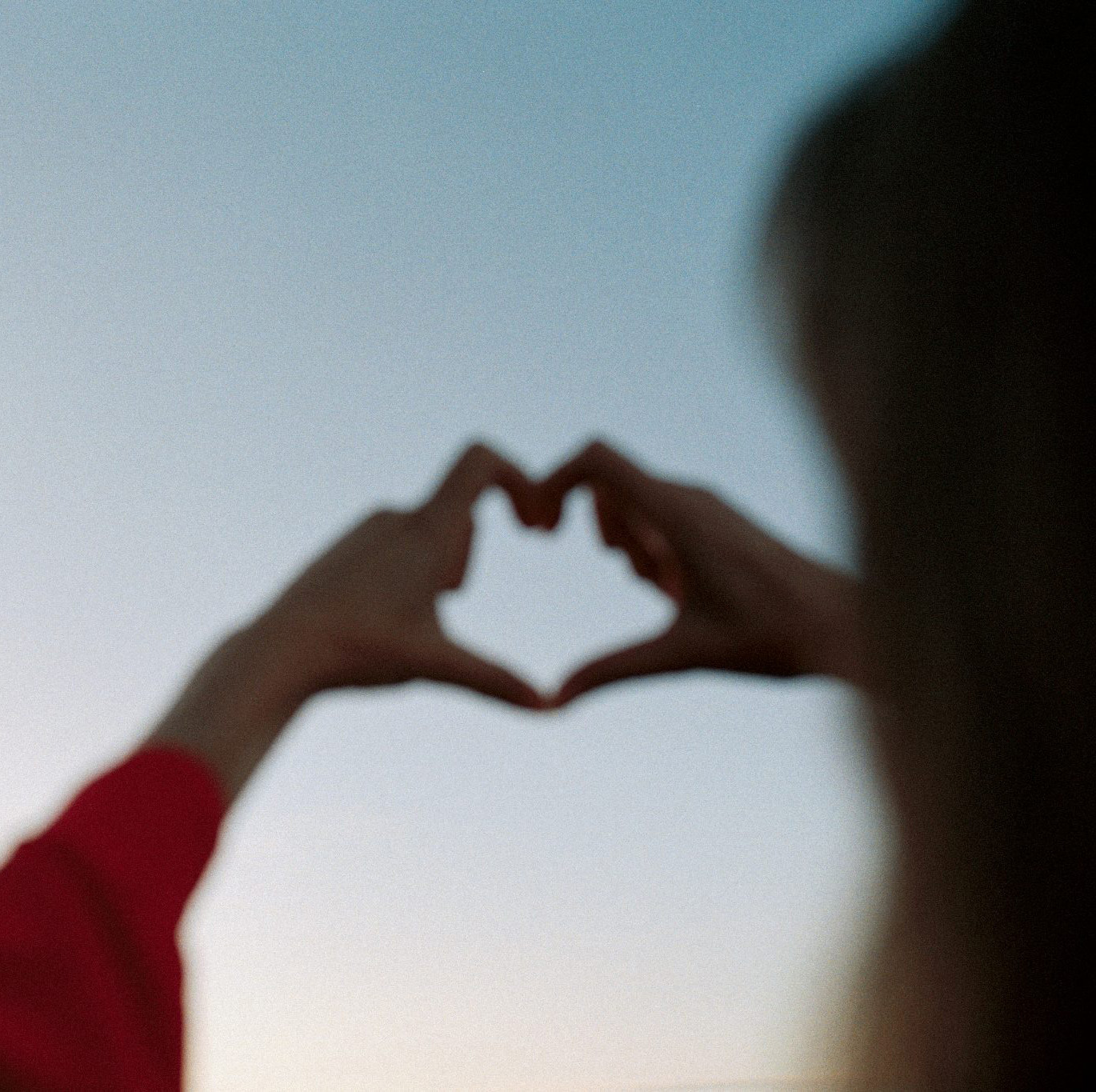Händer gör hjärta mot skyn.
