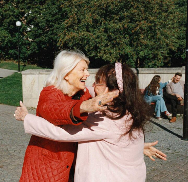 Två glada kvinnor omfamnar varandra.